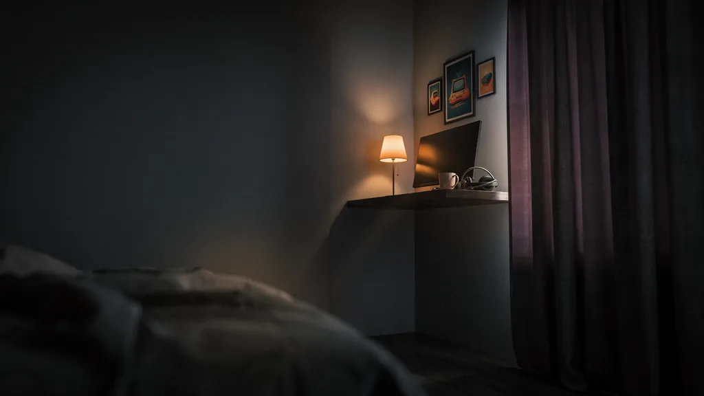 Small bedroom gaming corner with a compact desk and a three-print gallery cluster above it, with clear dark wall space around the frames